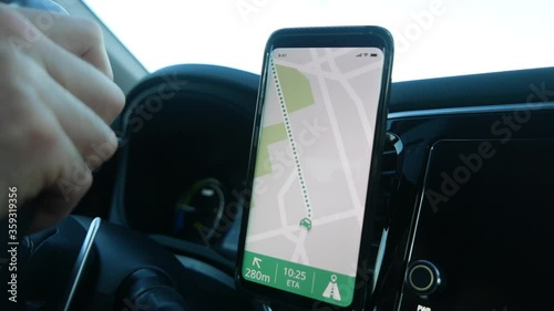 The driver of a vehicle using the GPS of his smartphone to navigate in his car. Closeup on the mobile device being used.