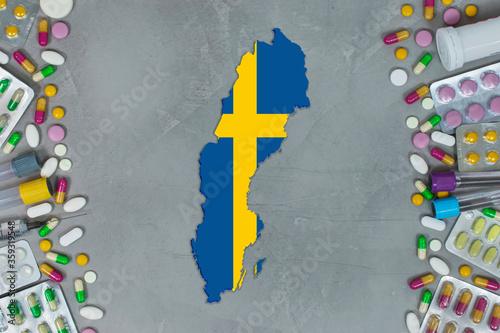 The Sweden State began research for treatment and medicine to combat the pandemic outbreak disease coronavirus. Medicine, pills, needles, syringes and Sweden map and flag on gray background.
