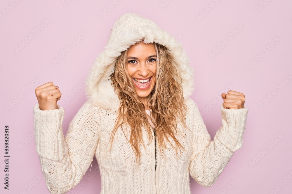 Φωτογραφία Young beautiful blonde woman wearing casual sweater with hood over isolated pink background celebrating surprised and amazed for success with arms raised and open eyes