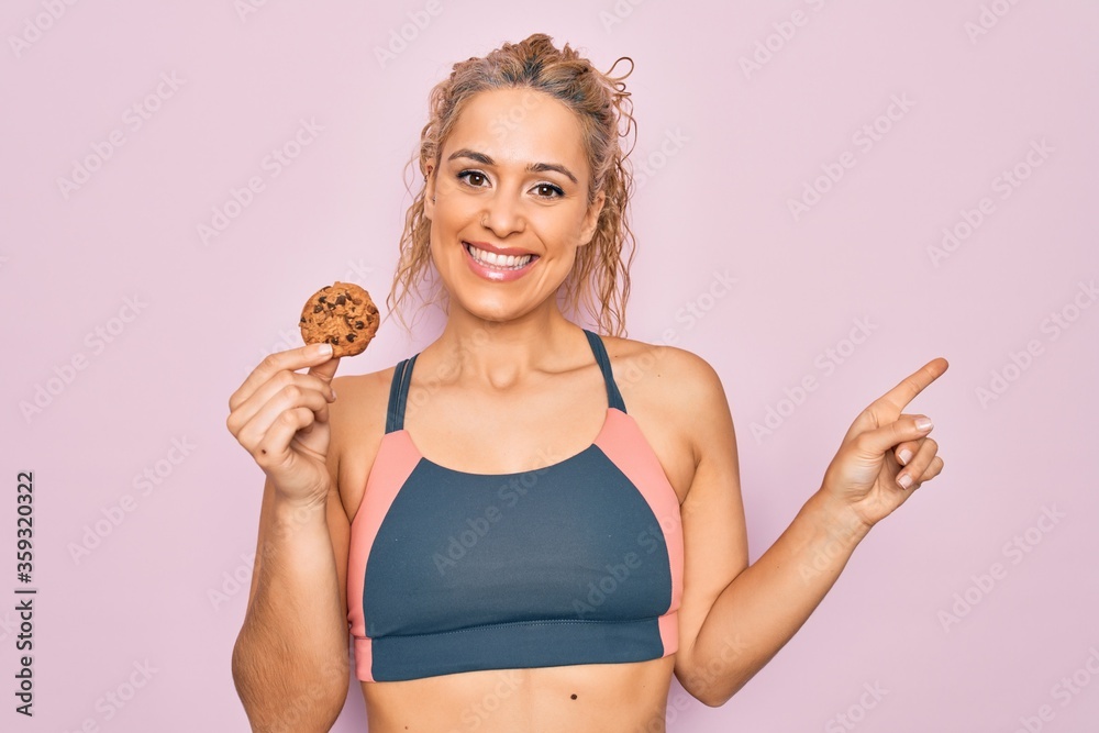 Φωτογραφία Young beautiful blonde sporty woman doing sport holding cookie over isolated pin