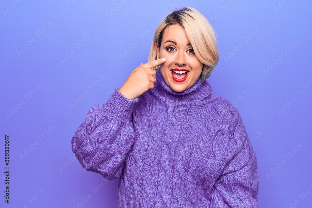 Beautiful blonde plus size woman wearing casual turtleneck sweater over purple background Pointing with hand finger to face and nose, smiling cheerful. Beauty concept Beautiful blonde plus size woman wearing casual turtleneck sweater over purple background Pointing with hand finger to face and nose, smiling cheerful. Beauty concept