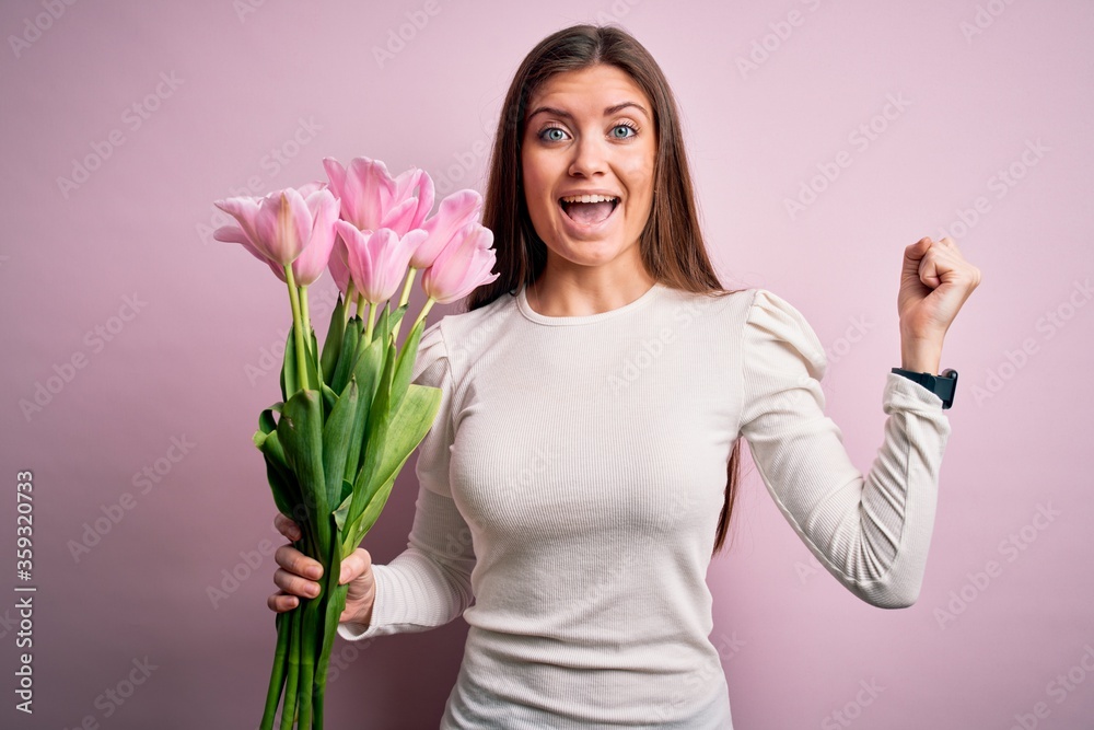 Young beautiful romantic woman with blue eyes holding beauty bouquet of pink tulips screaming proud and celebrating victory and success very excited, cheering emotion Young beautiful romantic woman with blue eyes holding beauty bouquet of pink tulips screaming proud and celebrating victory and success very excited, cheering emotion
