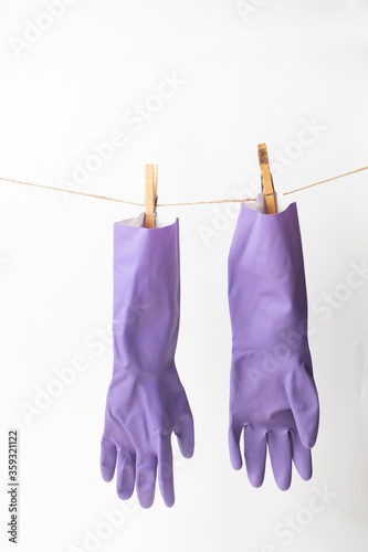 purple rubber gloves pinned on clothsline with white background