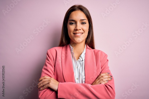 Young beautiful brunette woman wearing jacket standing over isolated pink background happy face smiling with crossed arms looking at the camera. Positive person.