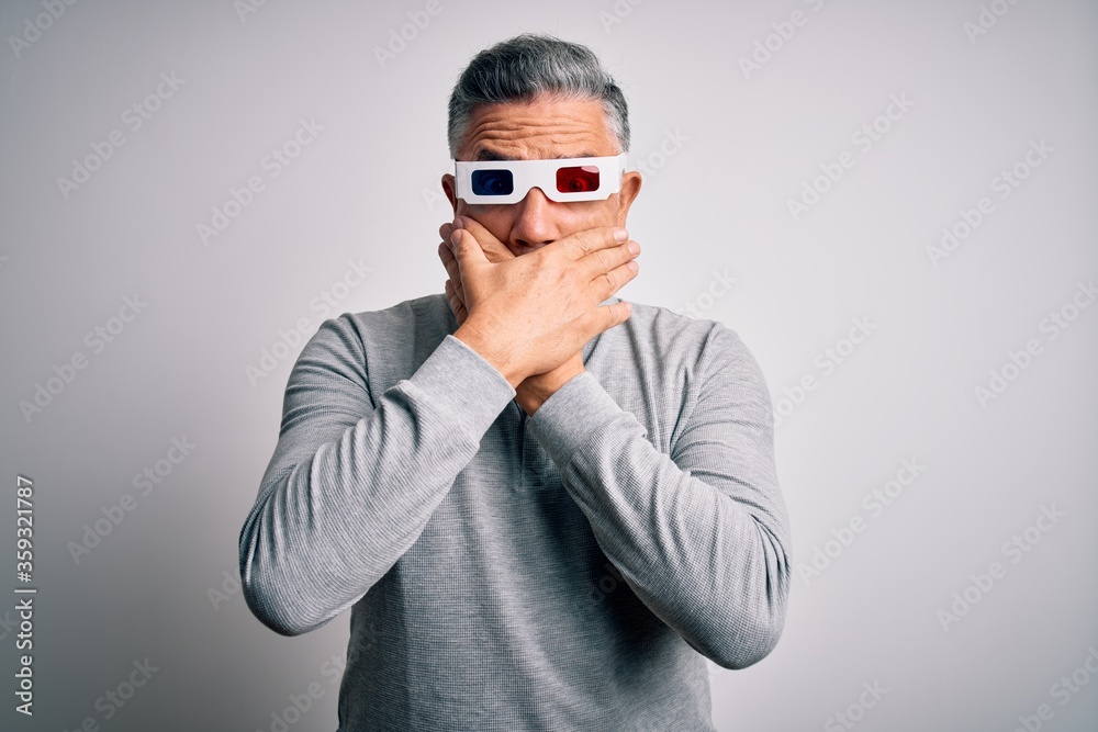 Middle age handsome grey-haired man using 3d glasses over isolated white background shocked covering mouth with hands for mistake. Secret concept.