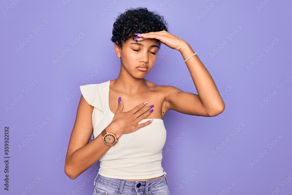 Young beautiful african american afro woman wearing casual t-shirt over purple background Touching forehead for illness and fever, flu and cold, virus sick