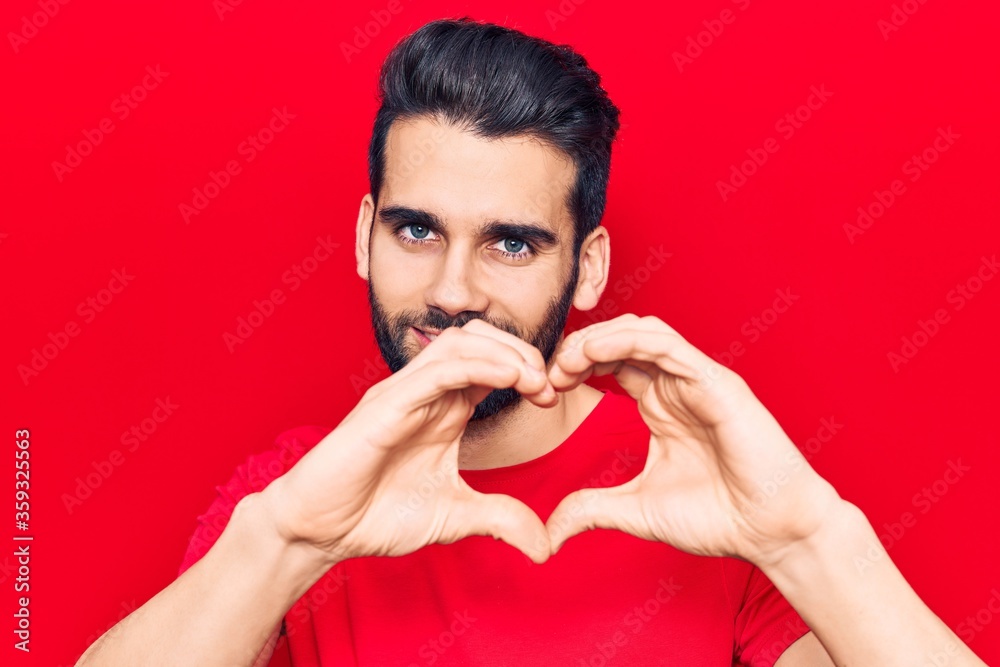 Young handsome man with beard wearing casual t-shirt smiling in love showing heart symbol and shape with hands. romantic concept. Young handsome man with beard wearing casual t-shirt smiling in love showing heart symbol and shape with hands. romantic concept.