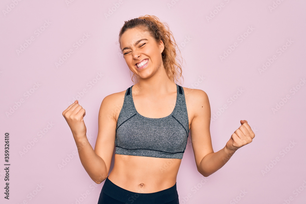 Young beautiful blonde sportswoman with blue eyes doing exercise wearing sportswear very happy and excited doing winner gesture with arms raised, smiling and screaming for success. Celebration