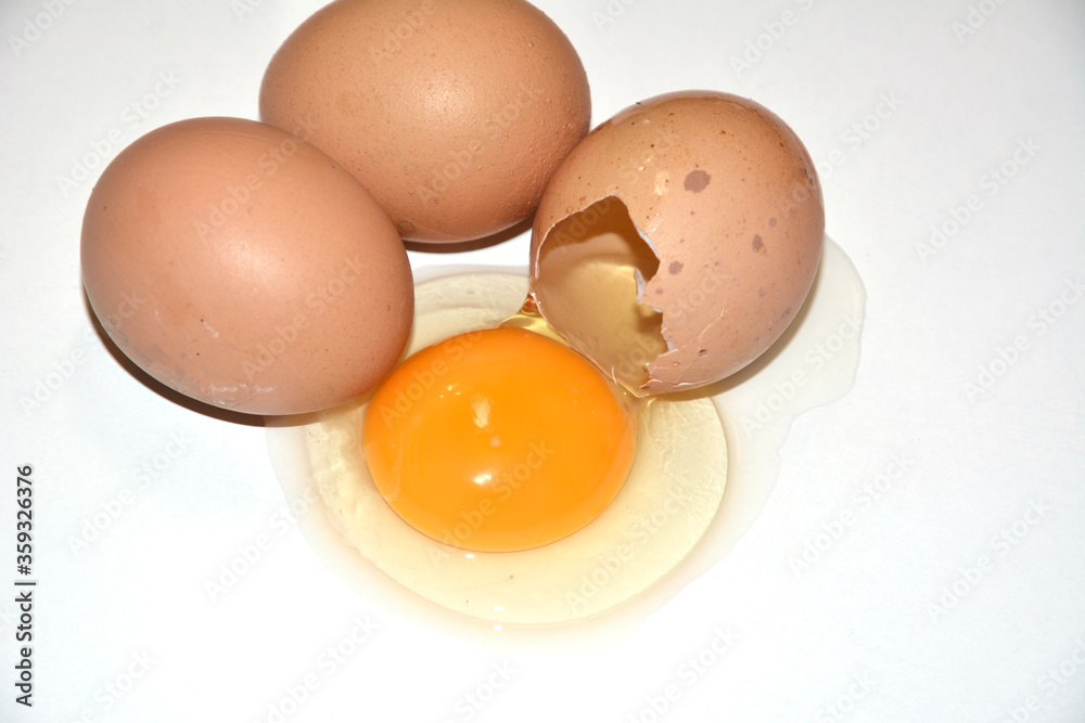 Three brown chicken eggs lie on an abelone Three brown chicken eggs lie on a white background. One egg is broken. Contained on the table, the yolk is visible. Idea for breakfast, for cooking Three brown chicken eggs lie on an abelone Three brown chicken eggs lie on a white background. One egg is broken. Contained on the table, the yolk is visible. Idea for breakfast, for cooking