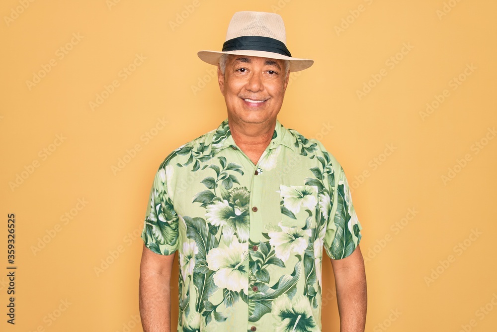 Middle age senior grey-haired man wearing summer hat and floral shirt on beach vacation with a happy and cool smile on face. Lucky person. Middle age senior grey-haired man wearing summer hat and floral shirt on beach vacation with a happy and cool smile on face. Lucky person.