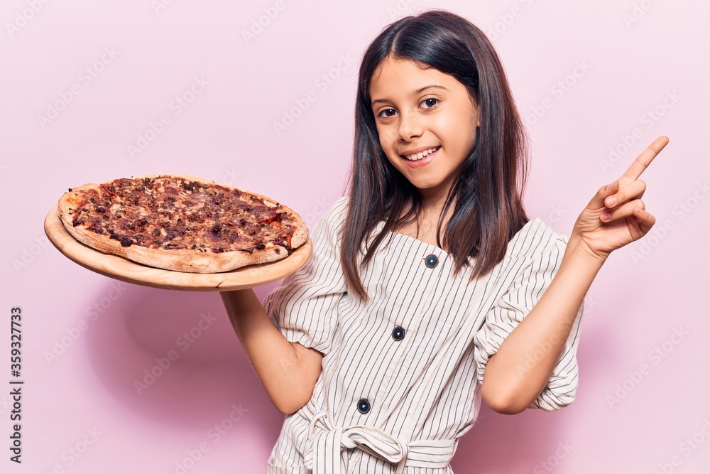 Beautiful child girl holding italian pizza surprised with an idea or question pointing finger with happy face, number one Beautiful child girl holding italian pizza surprised with an idea or question pointing finger with happy face, number one