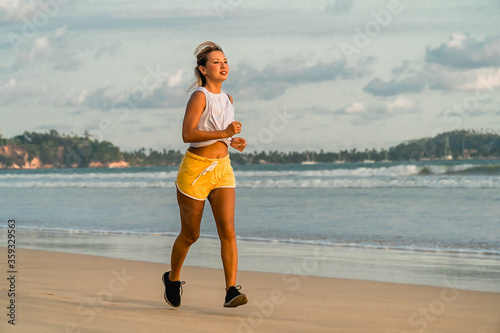 Fit young woman jogging on the beach. Sea shore running workout outdoor. Bright sports wear, positive active lifestyle