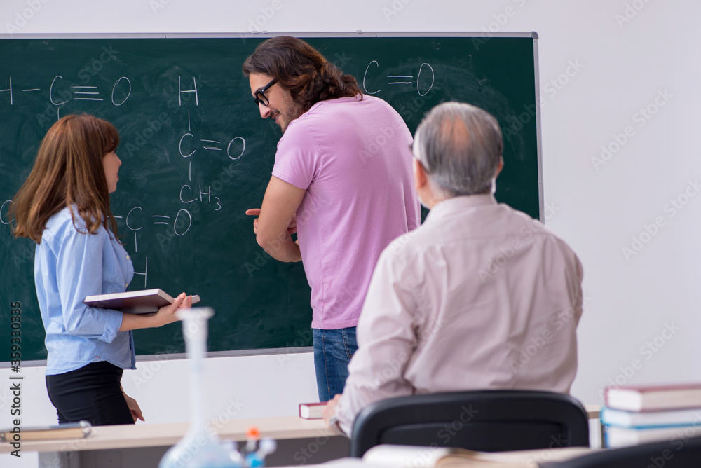 Old chemist teacher and two students in the classroom Old chemist teacher and two students in the classroom