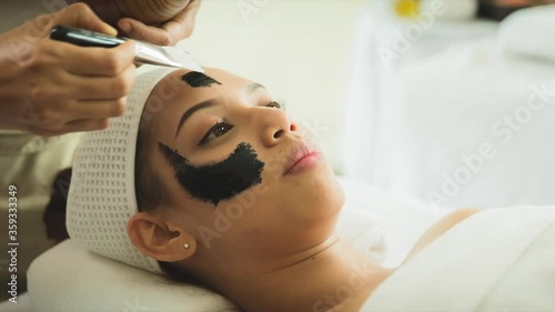 closed up young woman taking face masking treatment, by using natural black charcoal.