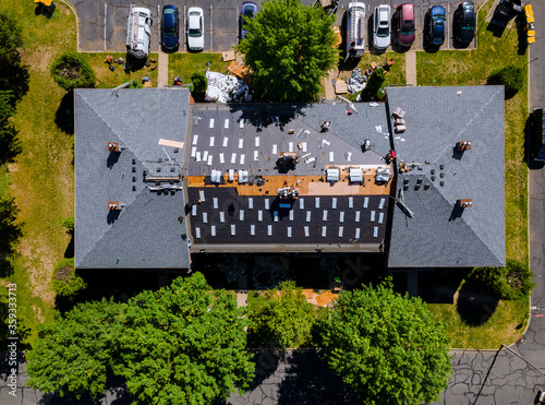 Foto A roofer nailing shingles with air gun, replacing roof cover protection being ap