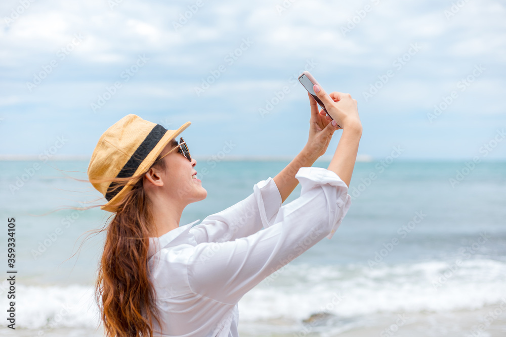 Happy young women wearing  sun glasses use mobile phones to take pictures on the beach While traveling.