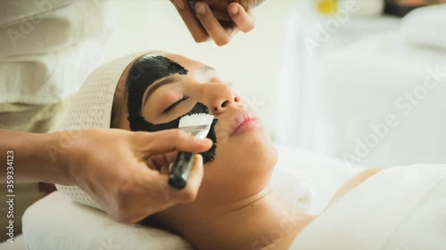 closed up young woman taking face masking treatment, by using natural black charcoal.