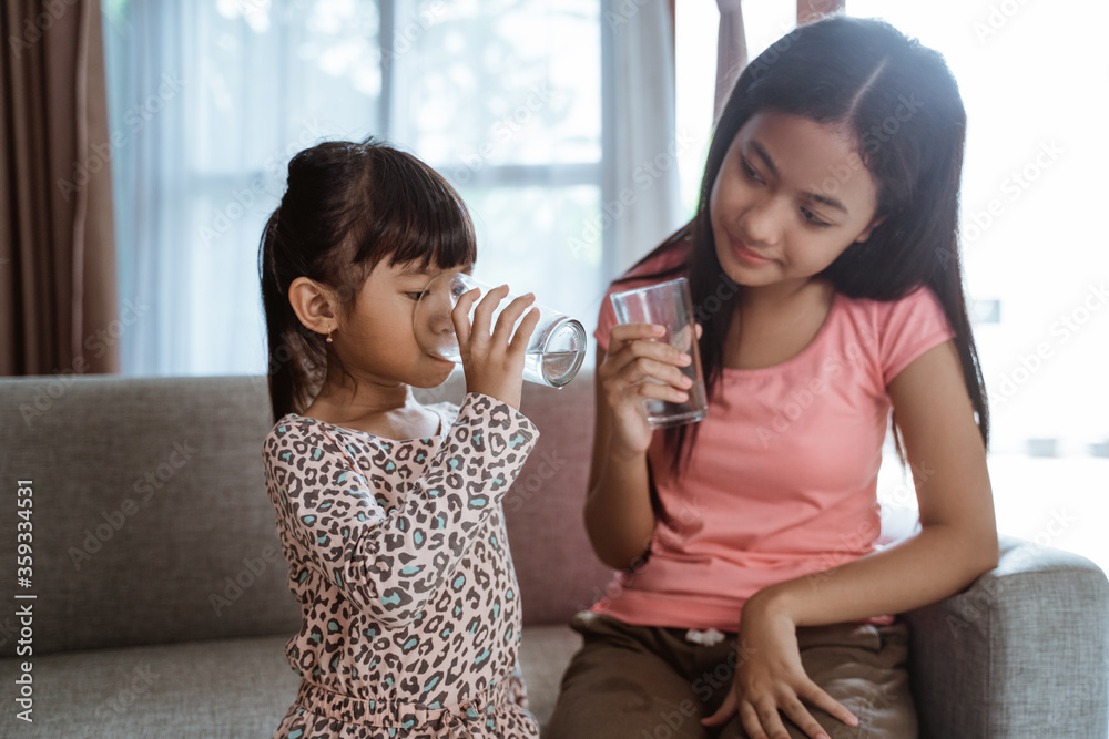 two kid sibling sister having a glass of water to drink at home two kid sibling sister having a glass of water to drink at home