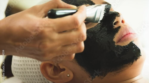 closed up young woman taking face masking treatment, by using natural black charcoal.