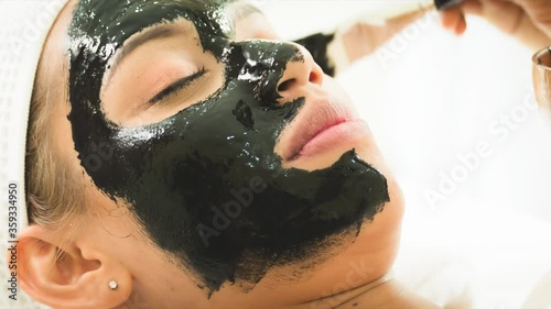 closed up young woman taking face masking treatment, by using natural black charcoal.