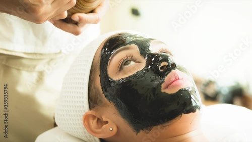 closed up young woman taking face masking treatment, by using natural black charcoal.