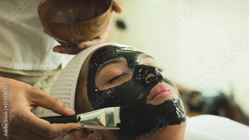 closed up young woman taking face masking treatment, by using natural black charcoal.
