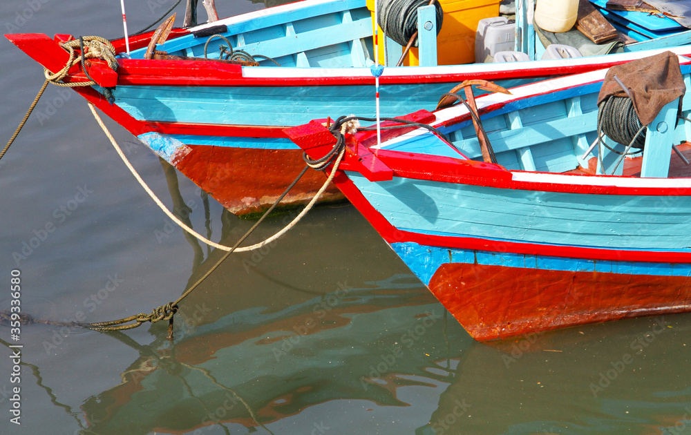 Colorful blue and red fishing boats in the Batang Arau river and port in Padang City in West Sumatra, Indonesia.