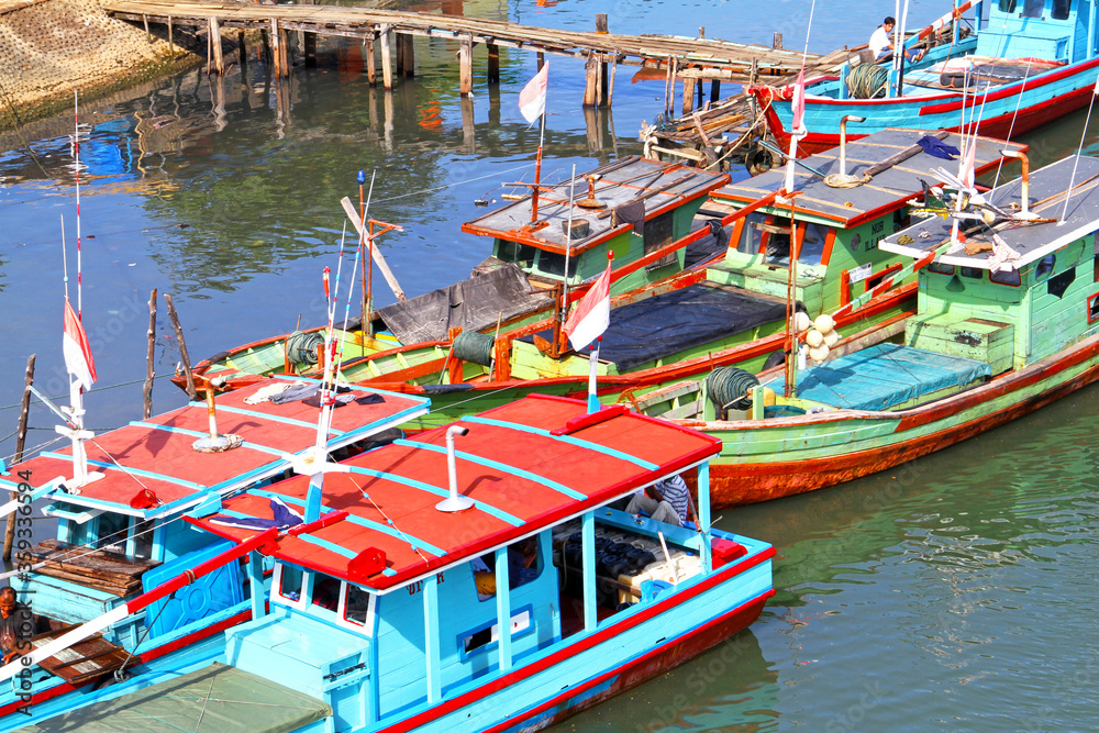 Colorful blue and red fishing boats in the Batang Arau river and port in Padang City in West Sumatra, Indonesia.