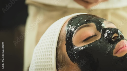 closed up young woman taking face masking treatment, by using natural black charcoal.