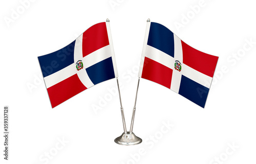 Dominican table flag isolated on white ground. Two flag poles with flags and Dominican flag on the table.
