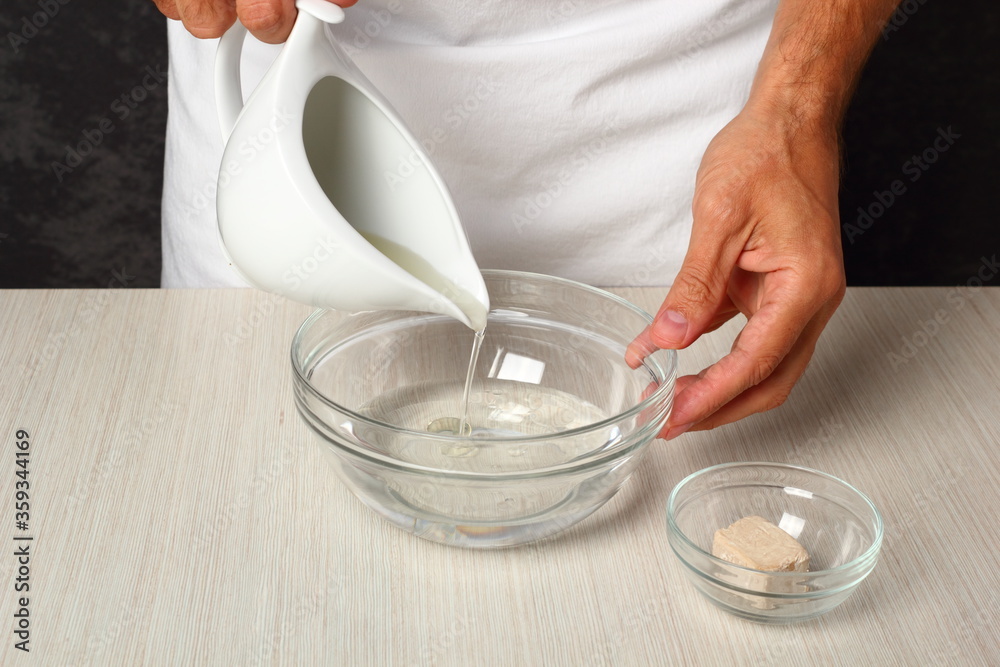 Making leaven - pouring oil into bowl with water. Making Flatbread. Making leaven - pouring oil into bowl with water. Making Flatbread.
