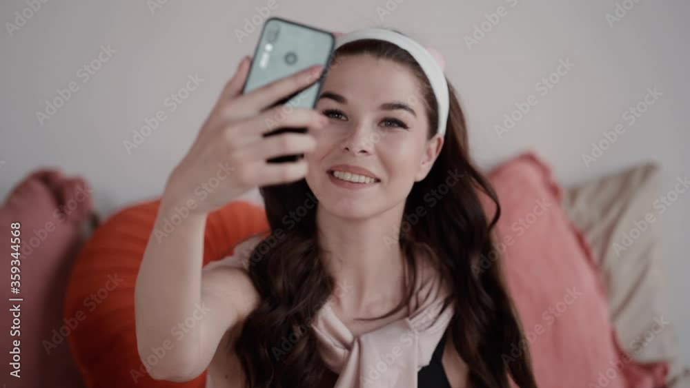 woman take cute selfie at home with pillows. young girl blogger photograph self portrait for social network. using smartphone to take picture. smiling, apartment, isolated concept woman take cute selfie at home with pillows. young girl blogger photograph self portrait for social network. using smartphone to take picture. smiling, apartment, isolated concept
