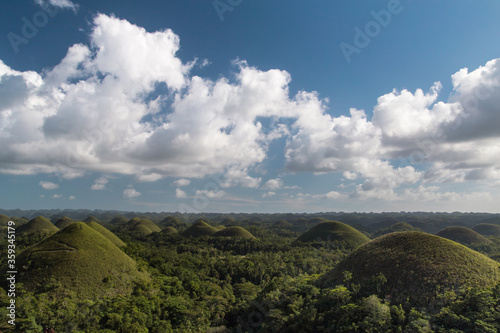 Chocolate hills on a sunny day with blue sky and clouds. Truffle shaped formations is the main attraction of Bohol island, Philippines