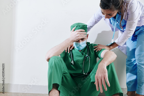 Nurse trying to reassure stressed surgeon after he lost his patient in difficut surgery photo