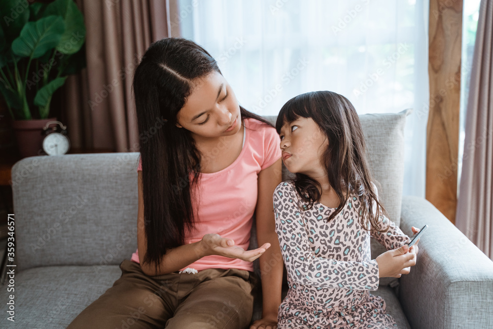 Fototapeta premium upset kid doesn't want to share her smartphone with sibling