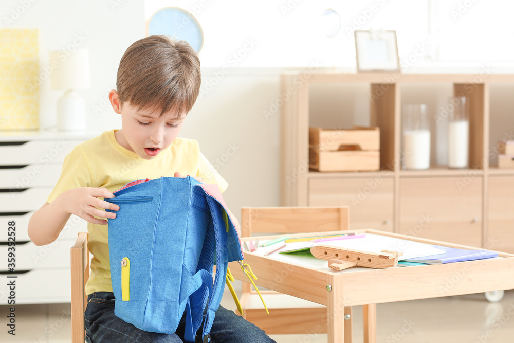 Cute little boy with schoolbag at home