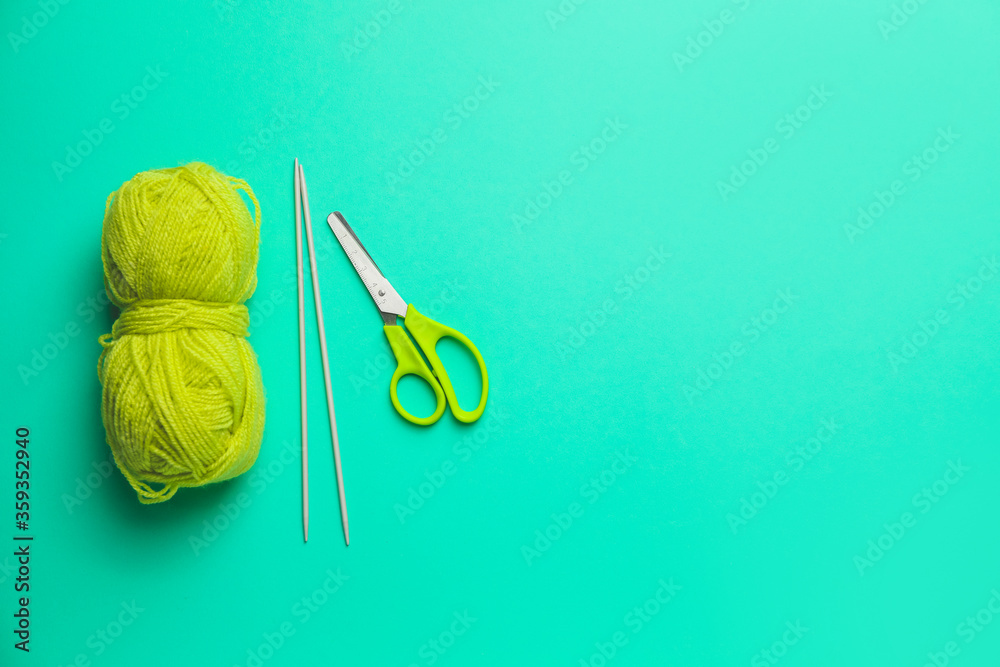 Scissors with knitting yarn and needles on color background Stock Photo