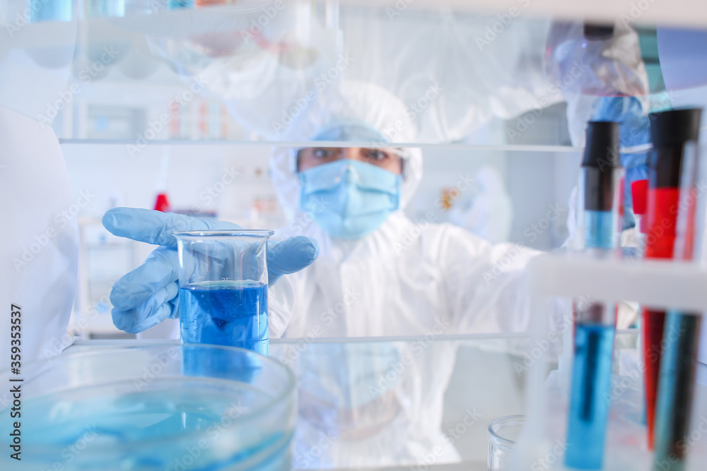 Scientist taking glassware from shelf in laboratory Scientist taking glassware from shelf in laboratory
