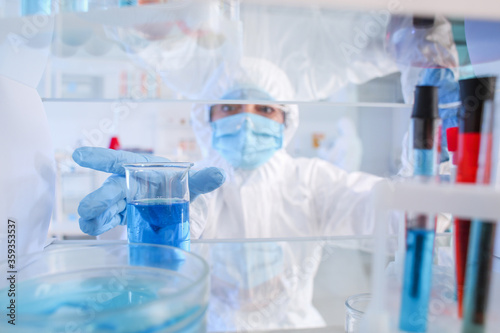 Scientist taking glassware from shelf in laboratory