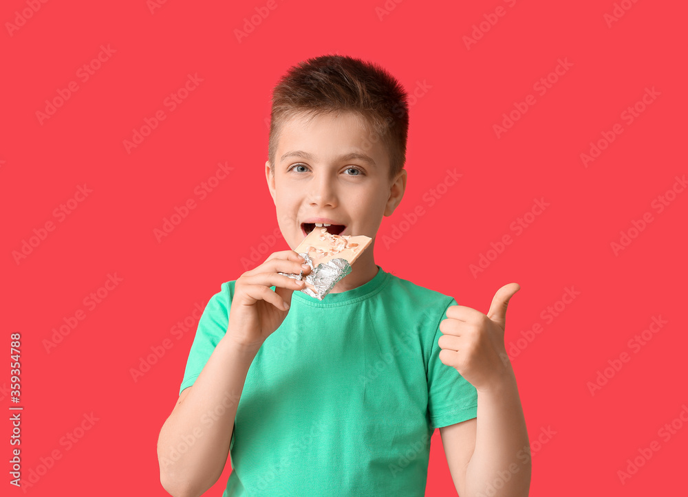 Cute little boy with chocolate showing thumb-up on color background Cute little boy with chocolate showing thumb-up on color background