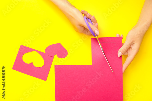 Woman cutting paper on color background