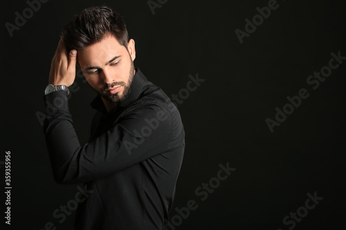 Handsome man with stylish hairdo on dark background © Pixel-Shot