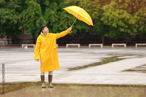 Young Asian man in raincoat...