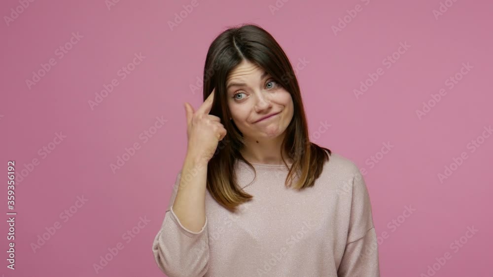 Insane idea! Displeased brunette young woman showing stupid gesture, looking disappointed with senseless dumb suggestion, accusing bad mind, crazy plan. indoor studio shot isolated on pink background Insane idea! Displeased brunette young woman showing stupid gesture, looking disappointed with senseless dumb suggestion, accusing bad mind, crazy plan. indoor studio shot isolated on pink background
