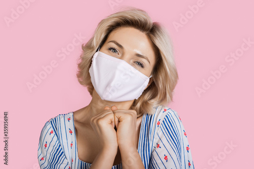 Stunning caucasian woman gesturing pleasure on a pink studio wall wearing a medical mask on face