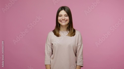 Hearing loss. Woman communicating with deaf-mute sign language, welcoming with friendly smile and making fingers shape saying nonverbal phrase Nice to meet you. studio shot isolated on pink background photo