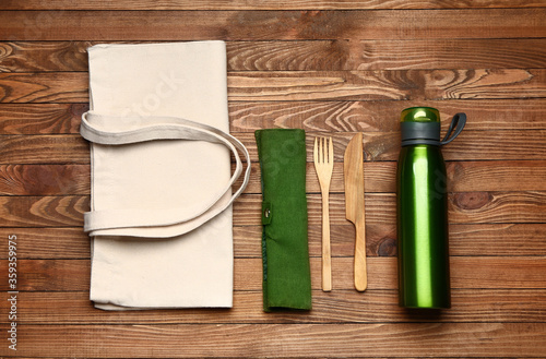 Eco bag with bottle and cutlery on wooden background