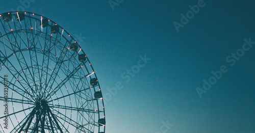 Glowing lights on Ferris wheel, resort nightlife, background, beautiful sky. High iso, grain