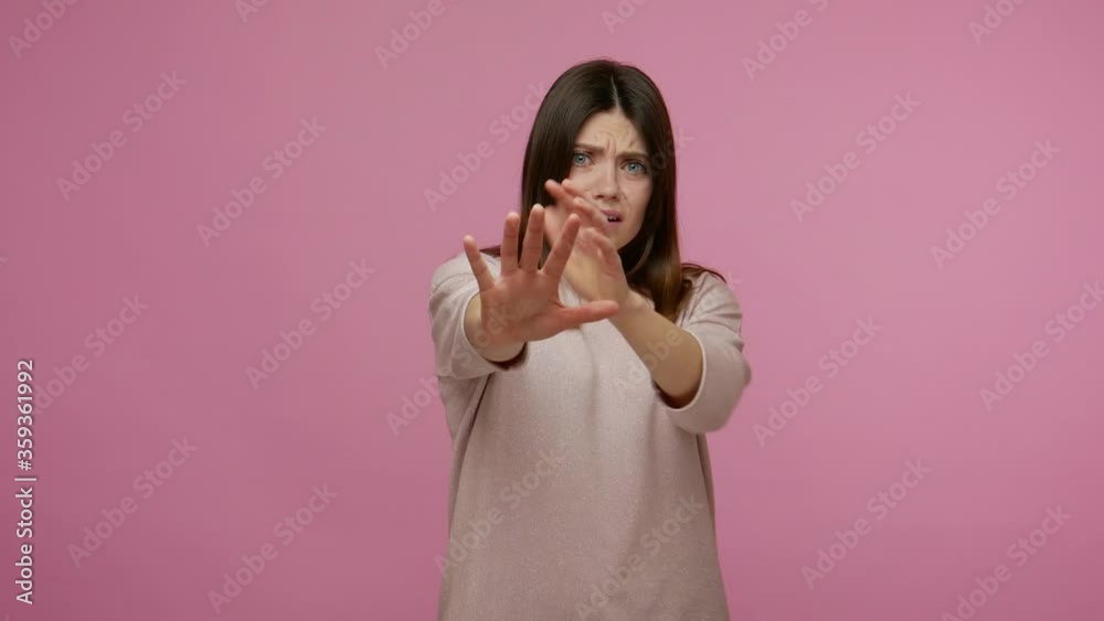 Witness of scary scene. Frightened woman closing her mouth not to shout and gesturing stop, looking at camera with terrified fearful expression, freaked out. studio shot isolated on pink background Witness of scary scene. Frightened woman closing her mouth not to shout and gesturing stop, looking at camera with terrified fearful expression, freaked out. studio shot isolated on pink background