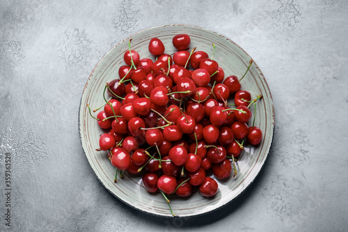 Plate with sweet cherry on table
